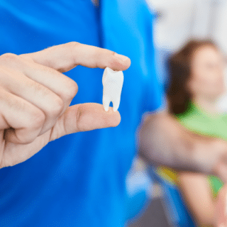 Dental specialist holding a tooth, representing oral surgery and tooth extractions