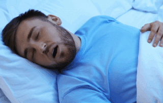 a man sleeping in bed, representing sleep apnea and dental health