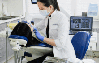 a woman in a white coat and mask working on a patient
