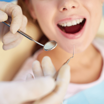 a close-up of a dentist holding a mirror to a patient's teeth, representing how preventative dental care saves money